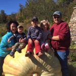 ralph snyder and his wife with their grandkids sitting on a giant pumpkin