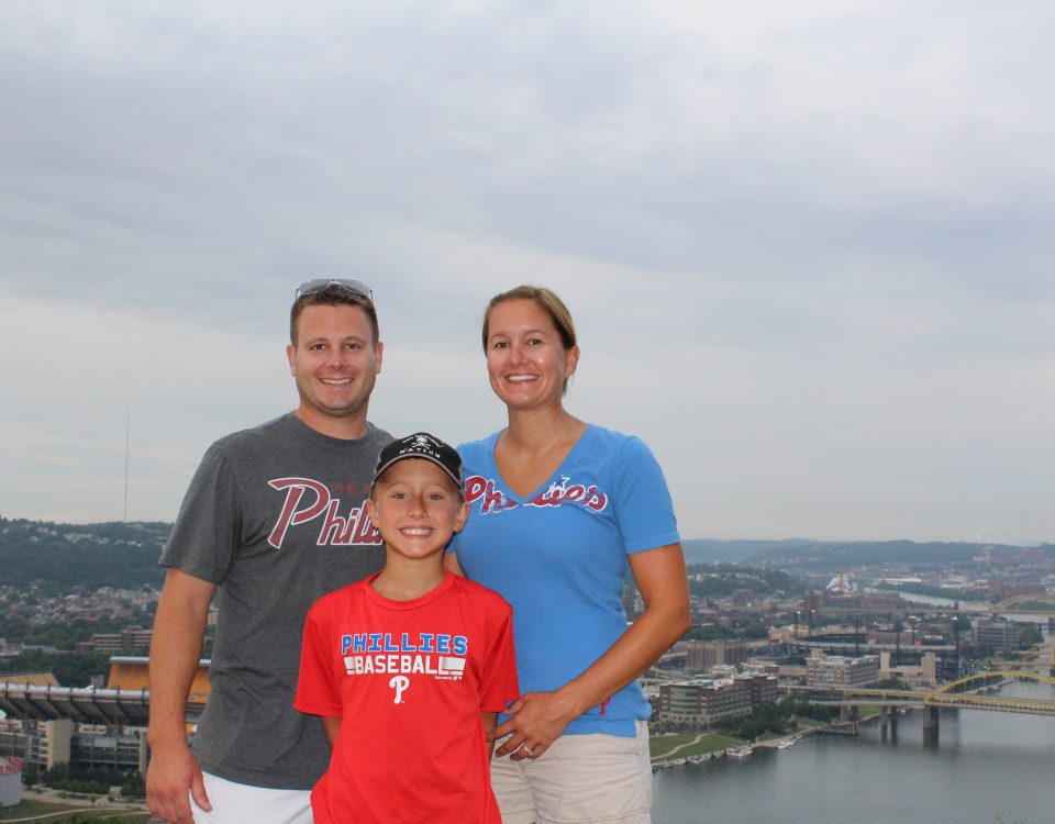 Shana Matz and her husband and son wearing Phillies shirts standing above Pittsburgh and Heinz Stadium