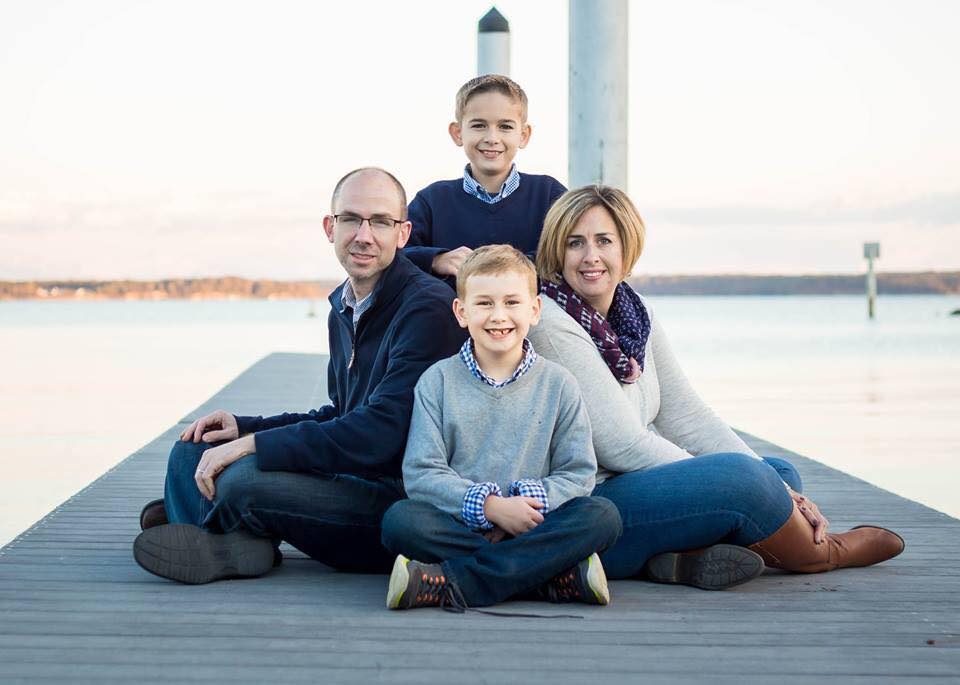 Mitzi Flint with her husband and sons sitting on the boat dock