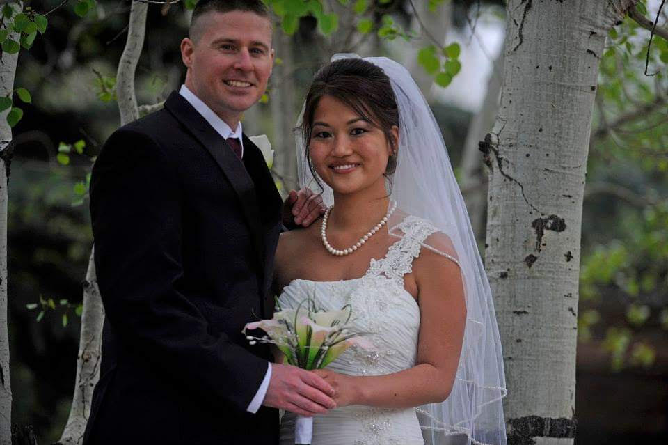 Nicole Stephens and Josh taking a wedding picture in front of trees