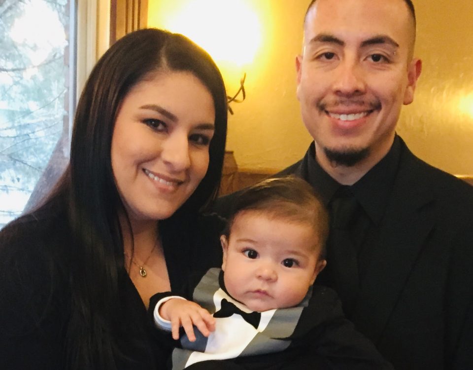 Sunnie and Andrew Andasola holding their son while all dressed up