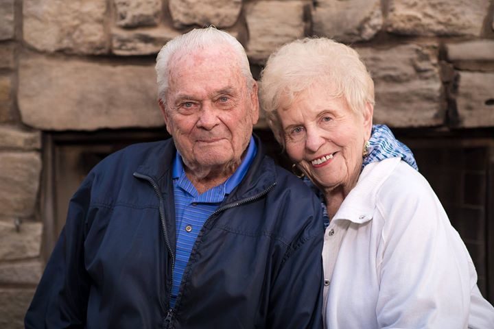 Doris Eastman and her husband in front of a thick rock fireplace