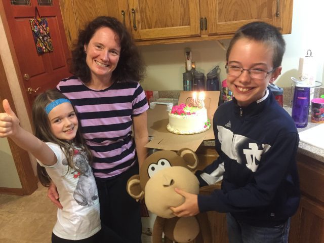 Jennifer and her kids celebrating her 43rd birthday with cake and a stuffed monkey