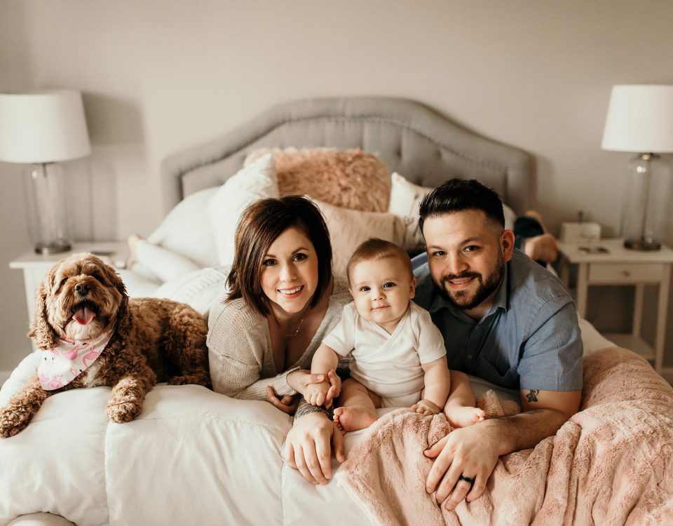 Brandy and Jeff Miller with their child and dog at the edge of their bed