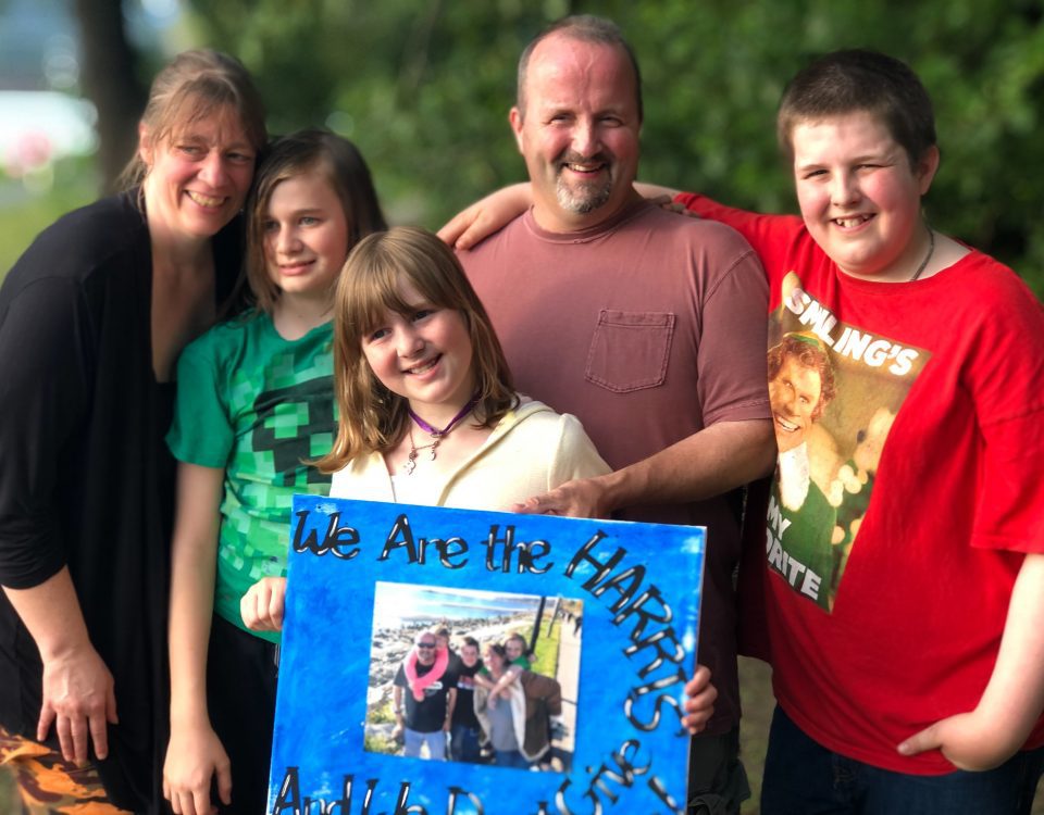 Cheryl Harris with her husband, son and two daughters holding a picture while taking a picture