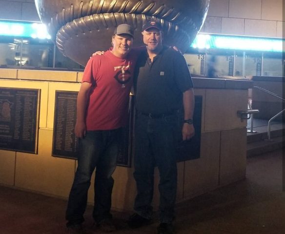 Jim Borkowski and his son outside Target Field in front of the giant baseball statue wearing Twins gear