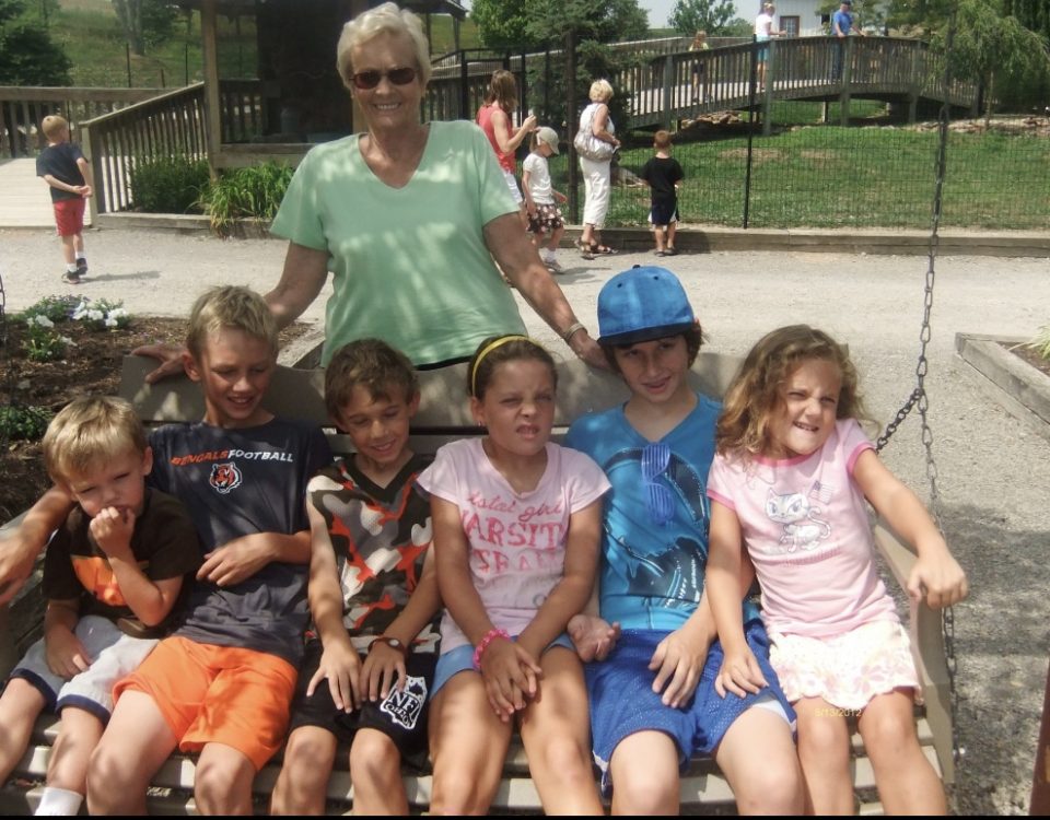 Barb Hedrick with all her grandkids on the swinging park bench