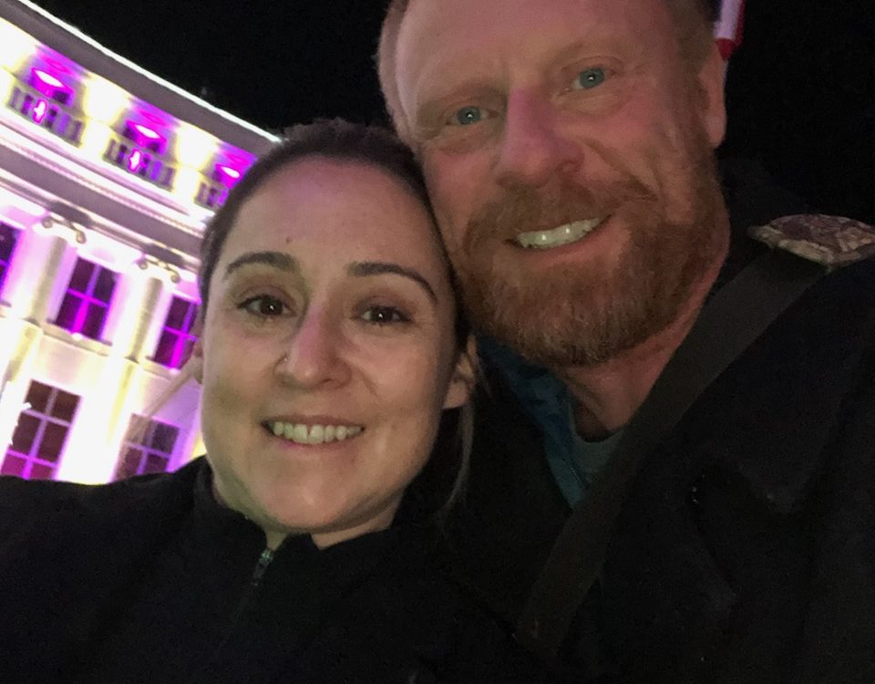 Angie and Kevin Hento in front of a White House with purple lights