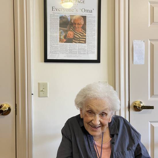 Everyone's Oma posing with her framed newspaper story in her senior care facility