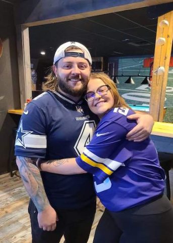 Stephanie Paradee and Ryan Read wearing clashing Dallas Cowboys Dak Prescott jersey and Minnesota Vikings Adam Thielen jersey