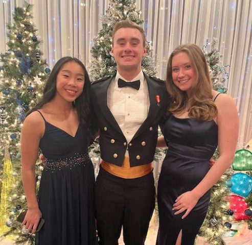 Lori Baylor's three kids dressed up in front of some Christmas trees