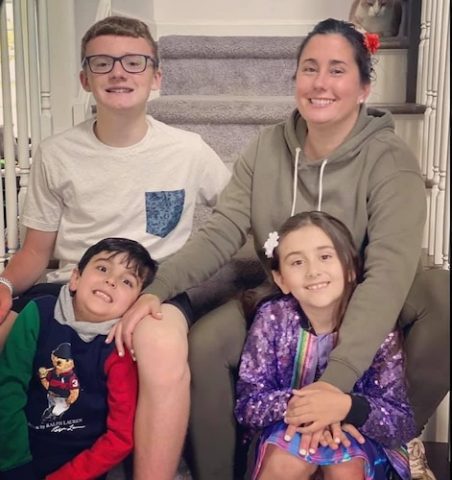 Jen Tomassi and her three children sitting together on the carpeted steps