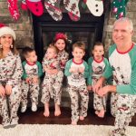 Jane Jewett with her husband and children wearing matching Christmas pajamas in front of the fireplace