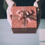 Person offering a present wrapped with a bow