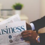 man opening newspaper with the title on he frontpage being 'Business'