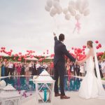 Husband and wife releasing balloons by the pool with all their guests across from them