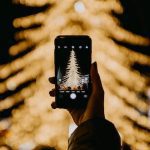 snapping a picture of someone snapping a picture of a Christmas tree