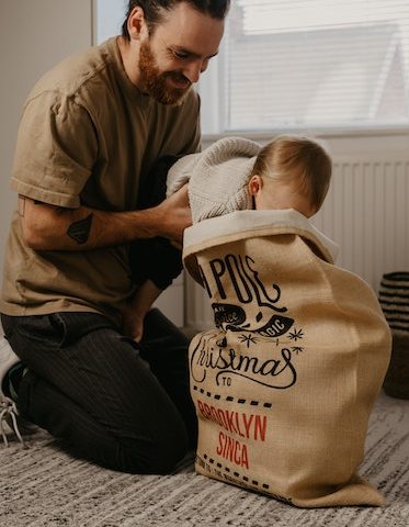 man helping baby open Santa sack