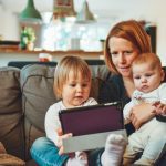 mom sitting on the couch holding her kids on the iPad